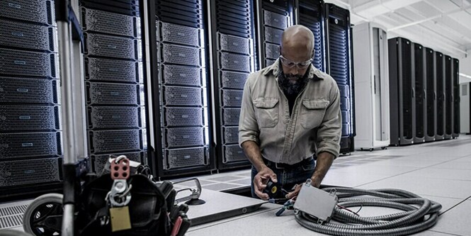 worker maintaining electrical equipment in datacenter
