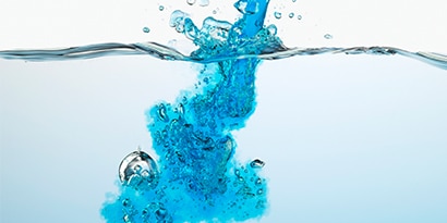 Blue liquid being poured from above into clear liquid
