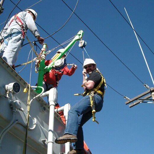 Image showing two workers wearing safety harnesses and helmets climbing a tall metal structure