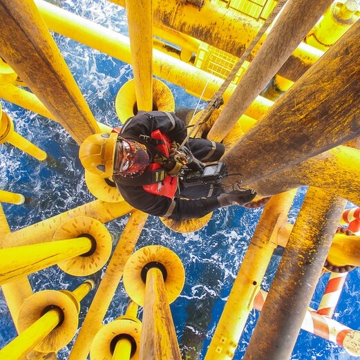 Image showing an upward view of interconnected yellow and blue industrial pipes with a central red valve