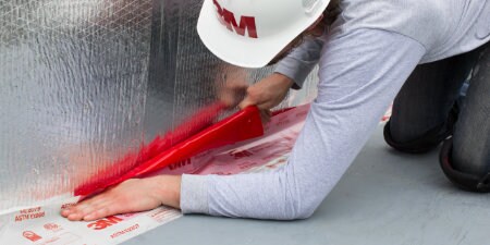 worker placing 3M Fire Barrier on floor seam
