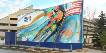 A large outdoor sign featuring a painted image of a bicyclist has bright colors protected by laminated film.
